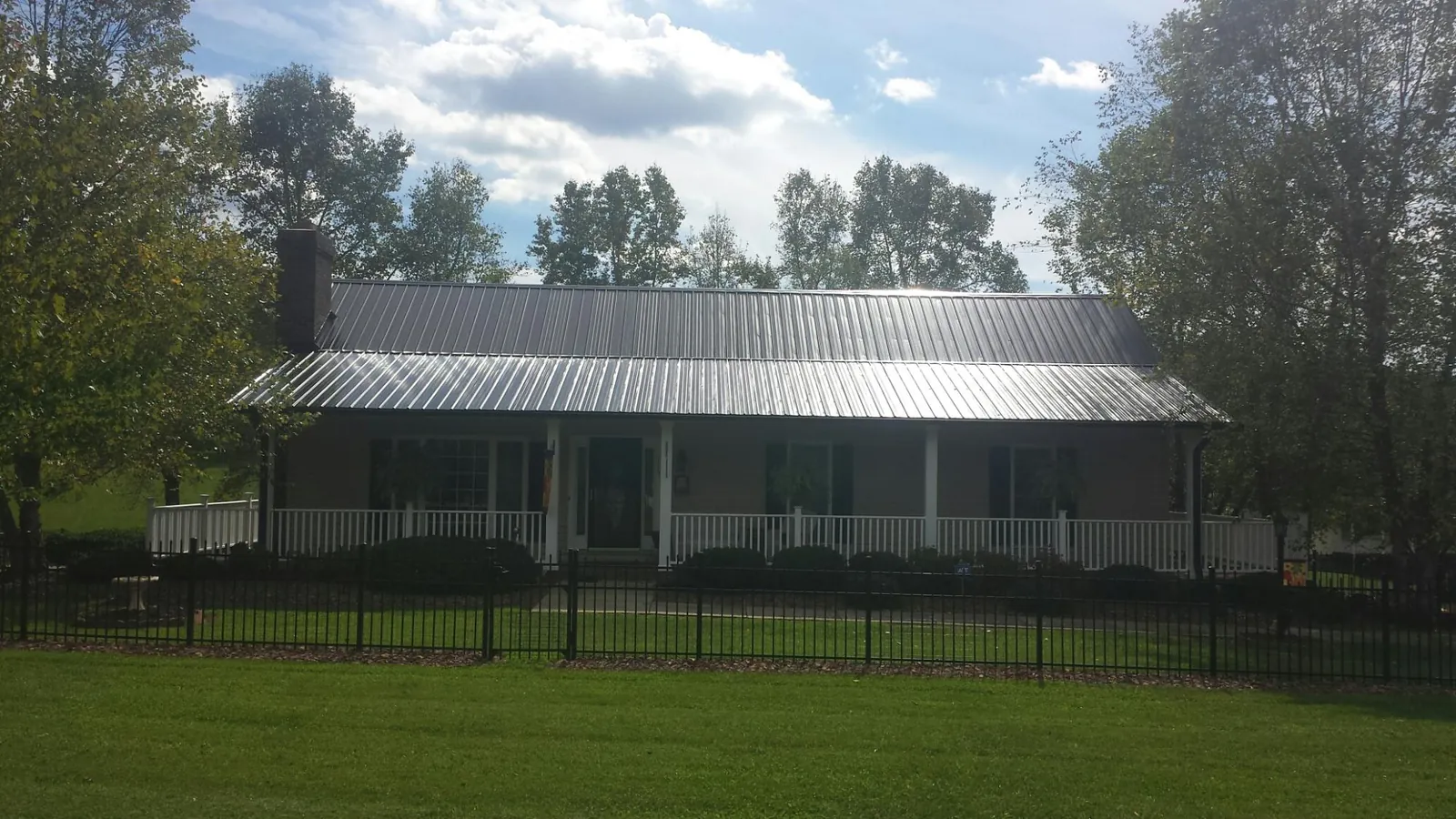 Gray metal roof on a brick ranch with a full width front porch — Gutter Guard Installation work by our crew in Hugo